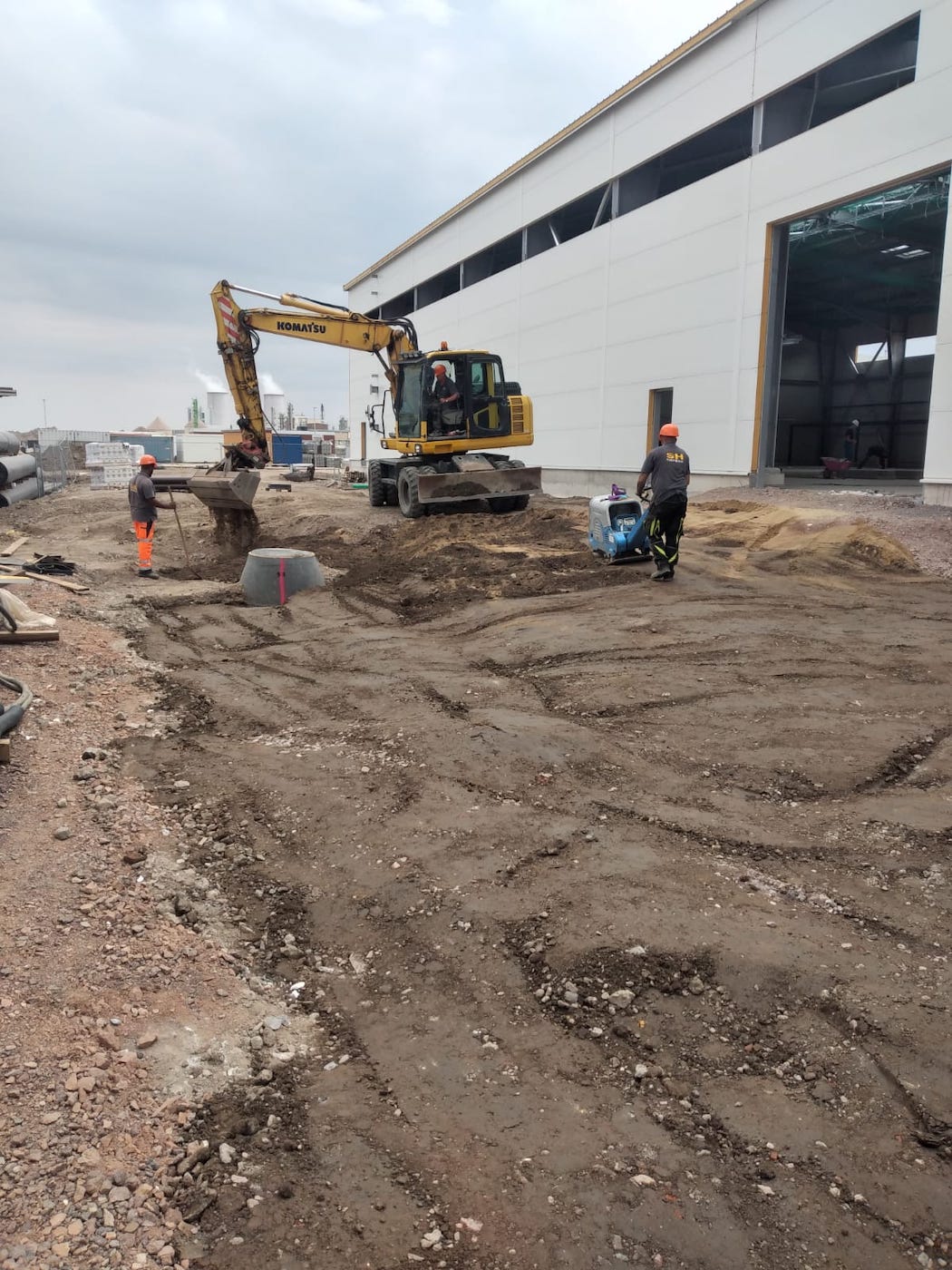 Bagger, Rüttelplatte und Mitarbeiter von Goki Bau auf einer Baustelle in Leuna